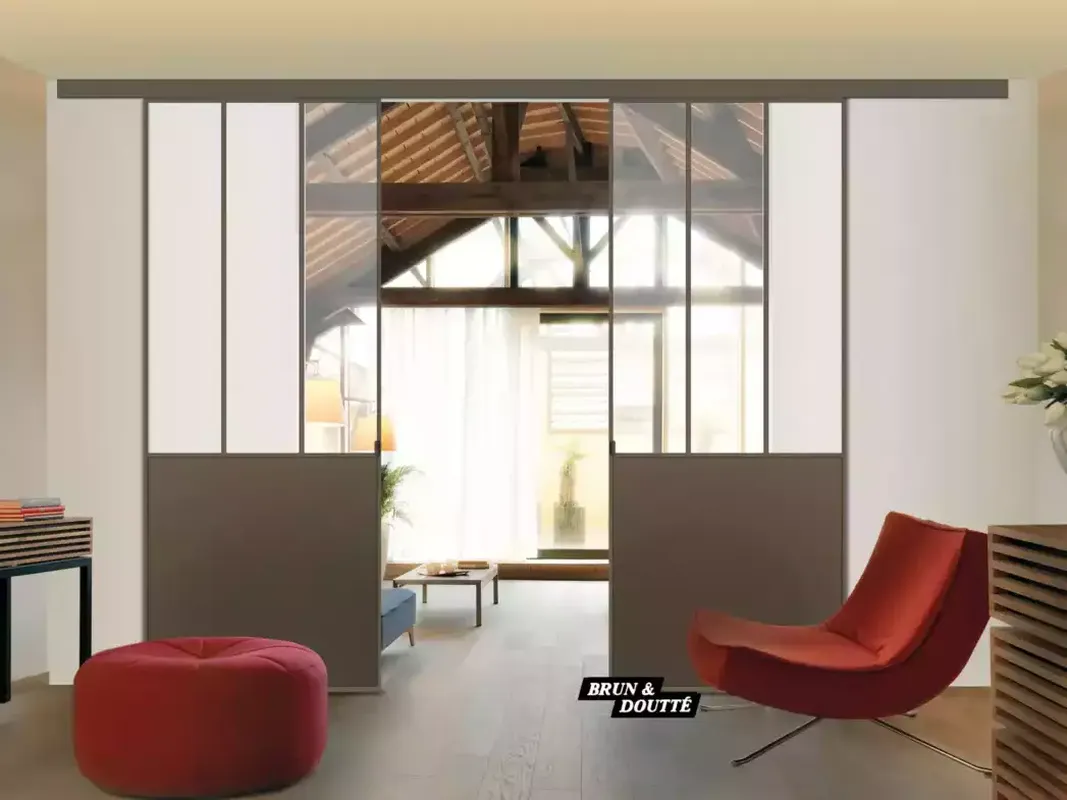 Cloison coulissante semi-vitrée style atelier, en aluminium, séparant un salon d'une autre pièce lumineuse