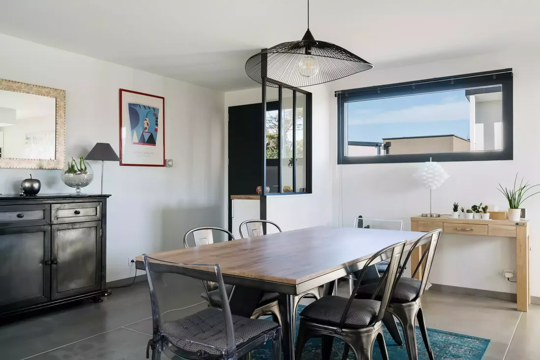 Fenêtre bandeau en aluminium noir dans une salle à manger au style industriel, optimisant la luminosité dans l'habitat moderne à Pau