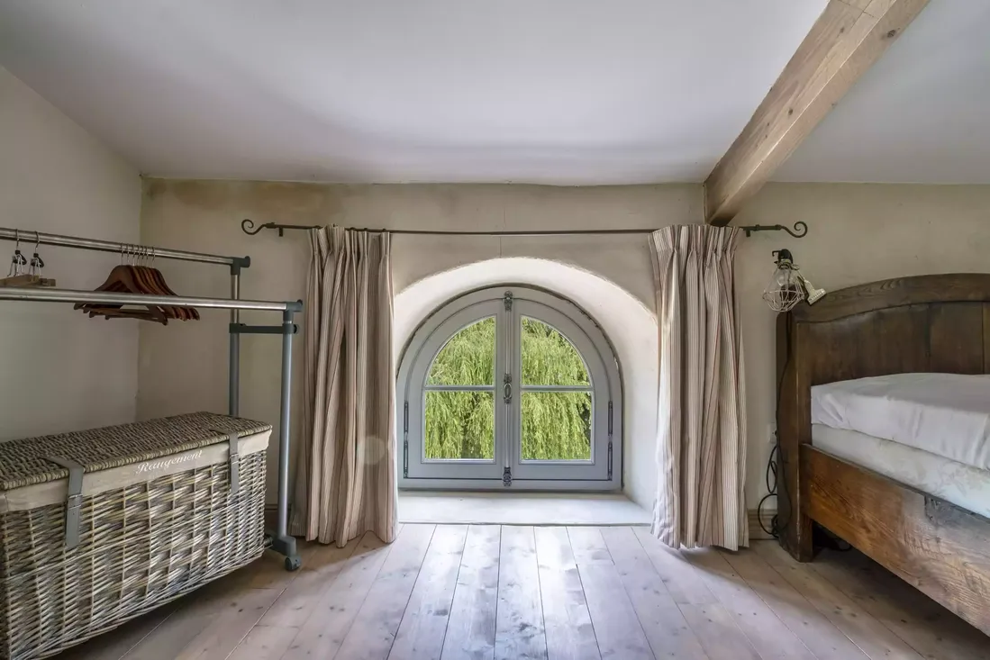 Fenetre en bois cintrée en arc avec petits carreaux dans une chambre rénovée sous les toits, typique du style maison de maître à Pau