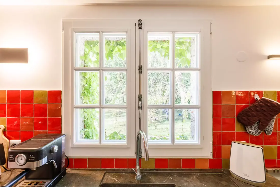 Fenêtre en bois blanche à petits carreaux, double vantaux, installée au-dessus d'un évier dans une cuisine rénovée à Pau