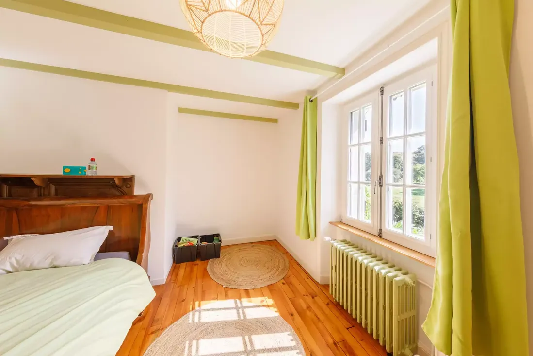 Fenêtre en bois blanche à petits carreaux dans une chambre de style traditionnel avec plancher bois, assurant une belle luminosité à Pau