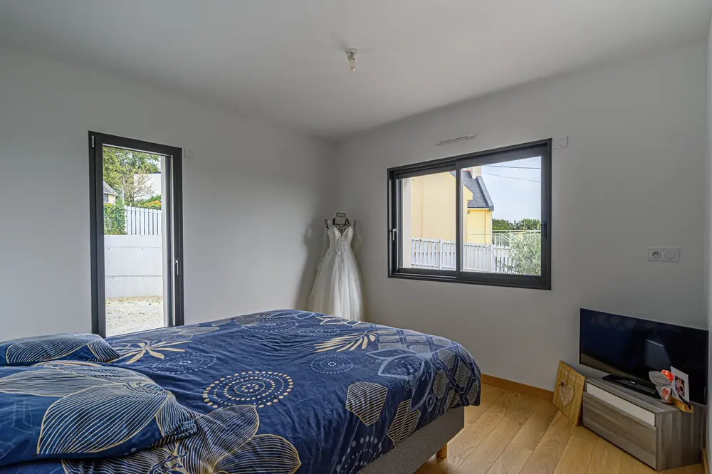 Fenêtre coulissante et porte-fenêtre en aluminium noir dans une chambre moderne, assurant luminosité et accès au jardin à Pau