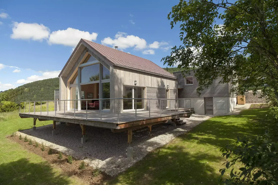 Grande façade vitrée en bois et baies coulissantes, intégrée à une maison d'architecte moderne avec terrasse sur pilotis dans la région de Pau