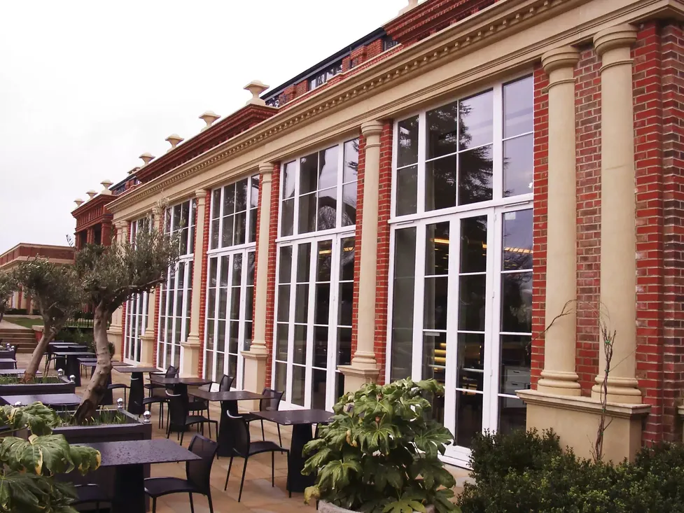 Grandes fenêtres et portes-fenêtres en bois blanc à petits carreaux sur une façade de restaurant avec terrasse, idéales pour les projets de rénovation commerciale à Pau