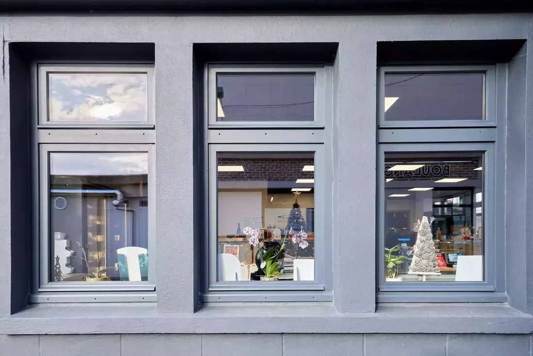 Fenêtres en bois gris anthracite sur deux niveaux, intégrées à la façade d'un commerce ou d'un bureau dans le centre-ville de Pau
