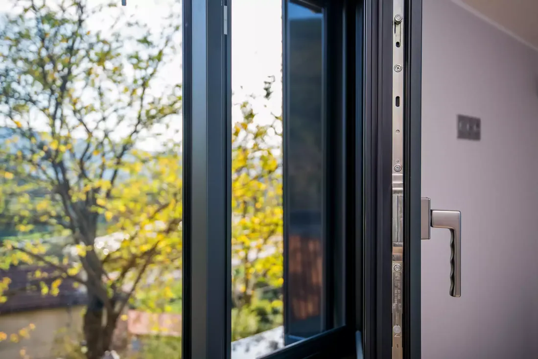 Gros plan sur le mécanisme de verrouillage et la poignée de fenêtre en aluminium, renforçant la sécurité et la qualité de la menuiserie à Pau