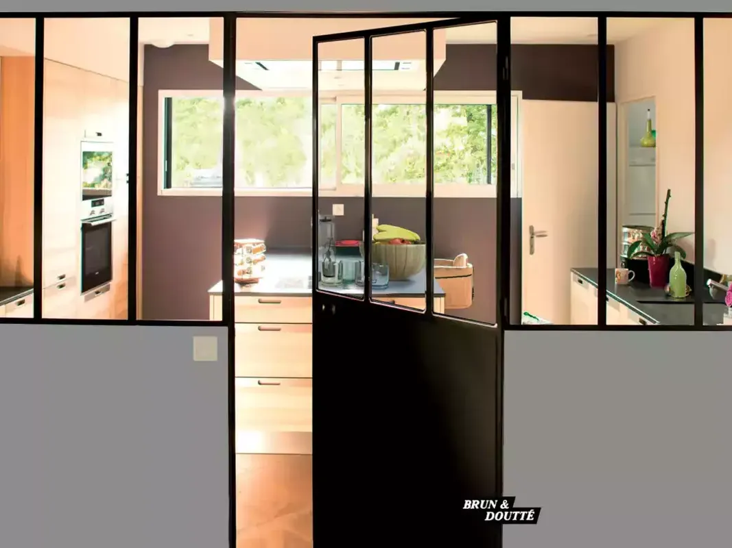 Porte battante d'intérieur style atelier, en acier noir avec soubassement, intégrée à une verrière de cuisine