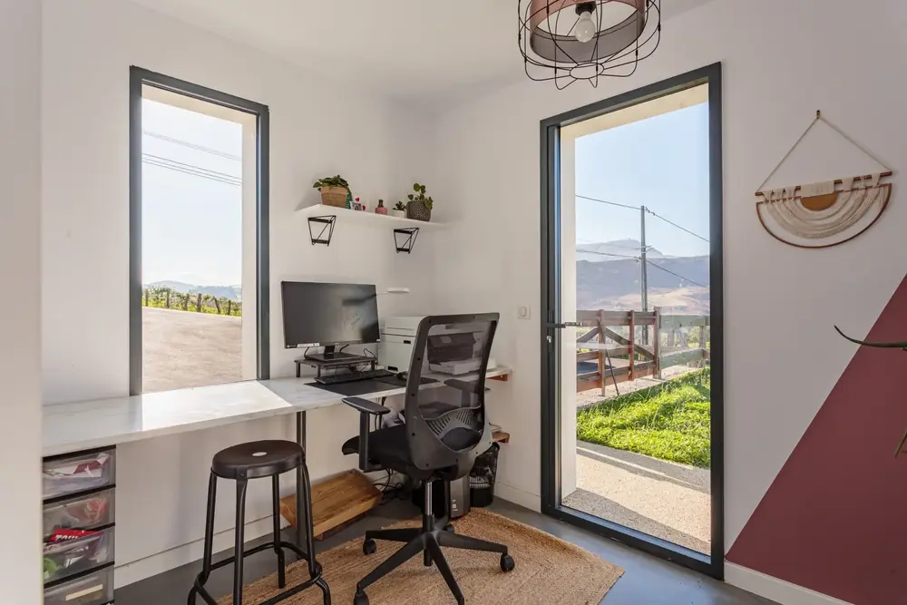 Porte-fenêtre et fenêtre haute en aluminium noir pour bureau à domicile, assurant luminosité et accès extérieur