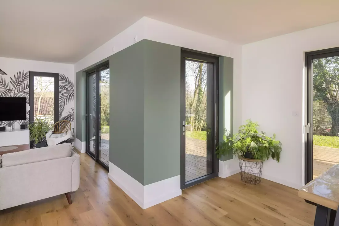 Multiples portes-fenêtres en aluminium gris anthracite, offrant un accès direct à la terrasse depuis le salon moderne