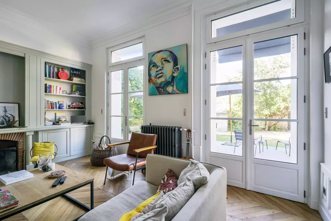 Portes-fenêtres en bois blanc à double vantaux dans un salon haussmannien rénové, offrant un accès direct au jardin à Pau