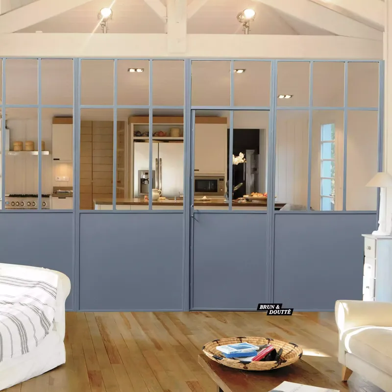 Grande verrière d'atelier avec soubassement plein gris, servant de cloison de séparation entre le salon et une cuisine ouverte à Pau