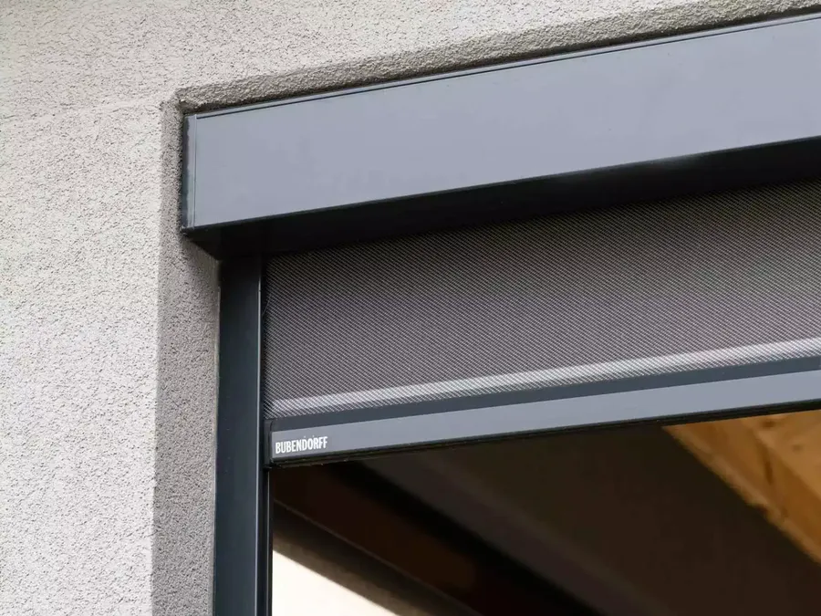 Gros plan technique du mécanisme d'un store screen ZIP motorisé, mettant en valeur le tissu anti-chaleur et la finition du caisson.