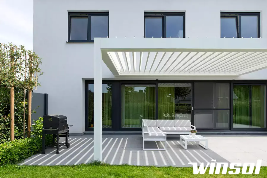 Pergola bioclimatique blanche Winsol à lames orientables installée sur une terrasse moderne de maison près de Pau.