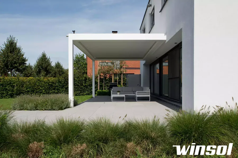 Pergola blanche Winsol à toile rétractable installée sur une grande terrasse adossée à une maison moderne