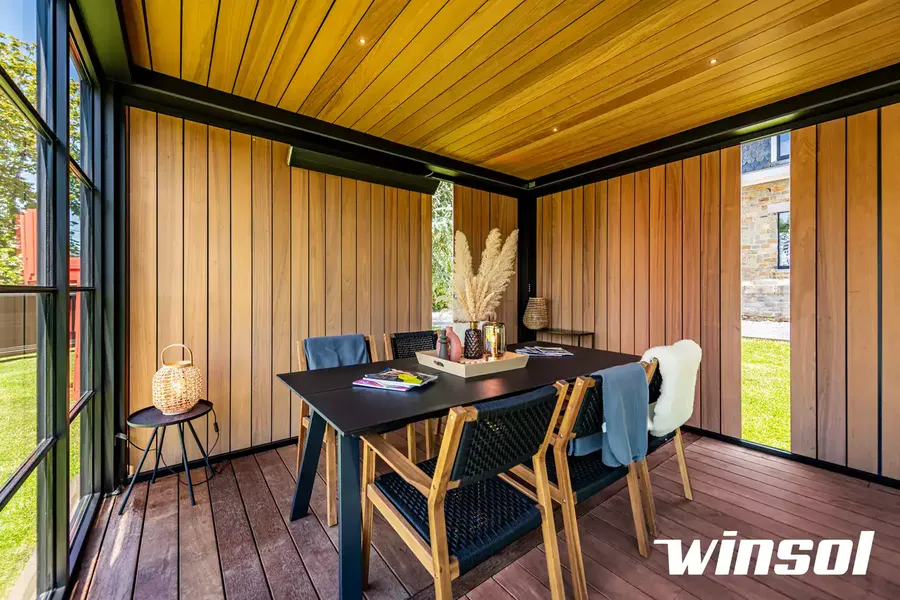 Intérieur de pergola à toit plein fermée avec revêtement en bois, aménagée en salle à manger extérieure. Pose de pergola bioclimatique près de Pau.