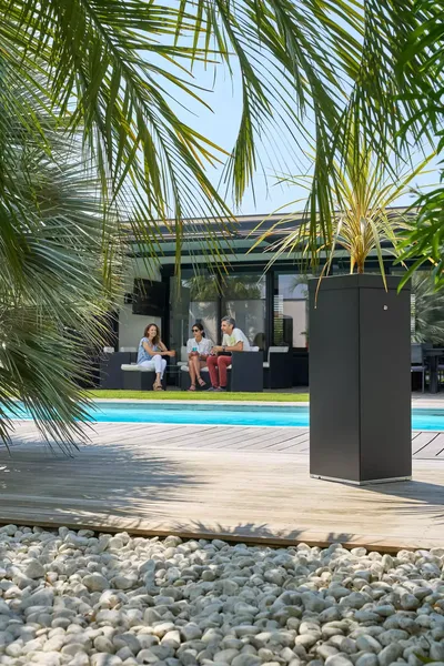 Borne à moustique discrète aménagée en pot de fleur, protégeant le jardin et la zone de piscine d'une maison résidentielle à Pau.