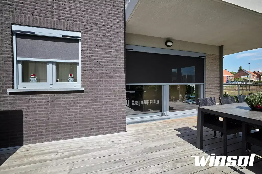 Store anti chaleur (screen vertical) sur une façade en briques, installé sur une terrasse en bois