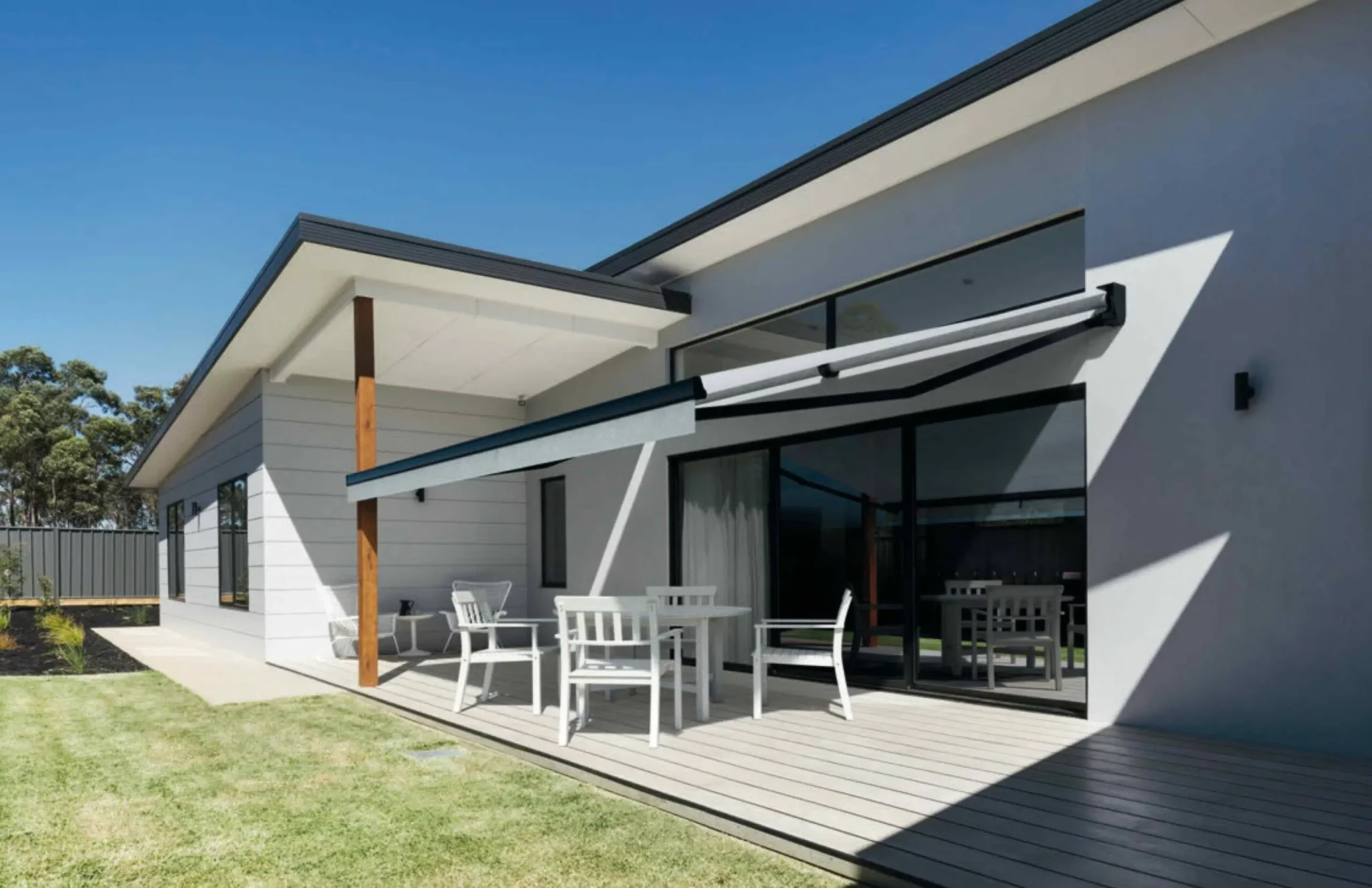 Store banne design gris sur façade de maison moderne, offrant de l'ombre sur une terrasse en bois composite à Pau.