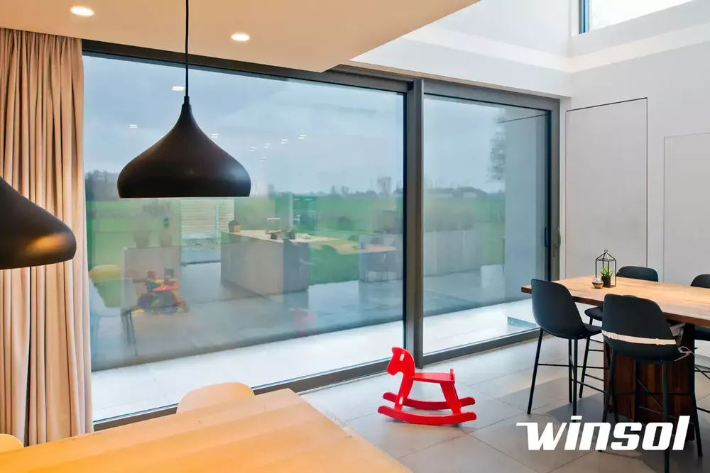 Store screen intérieur transparent pour très grande baie vitrée, filtrant la chaleur sans masquer la vue panoramique (protection solaire anti-chaleur)