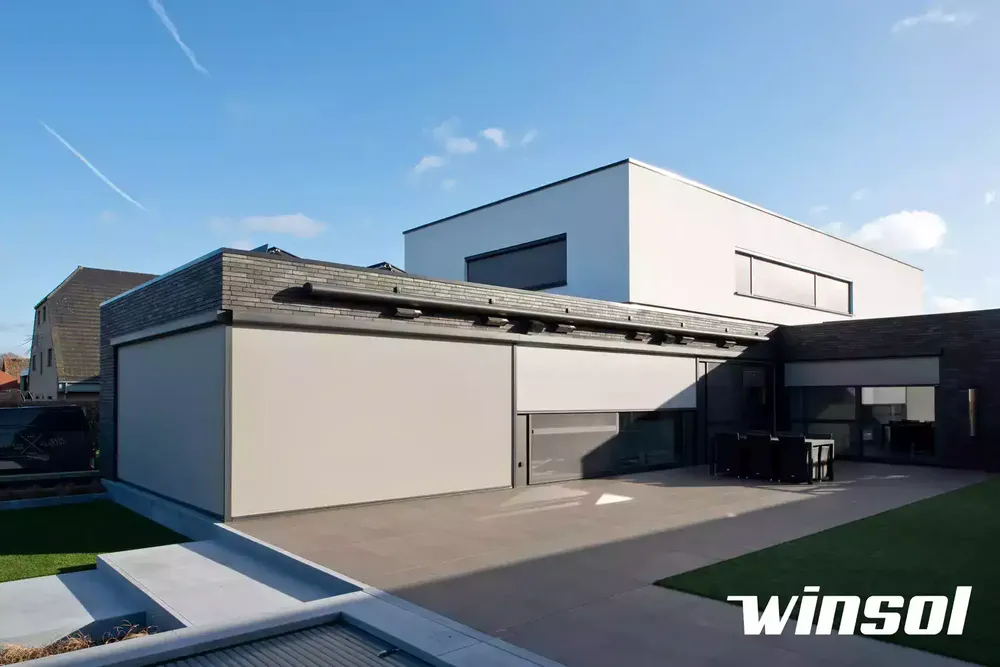 Stores screens ZIP motorisés couvrant une grande baie vitrée sur une maison d'architecture moderne à Pau, pour une protection solaire et du vent.