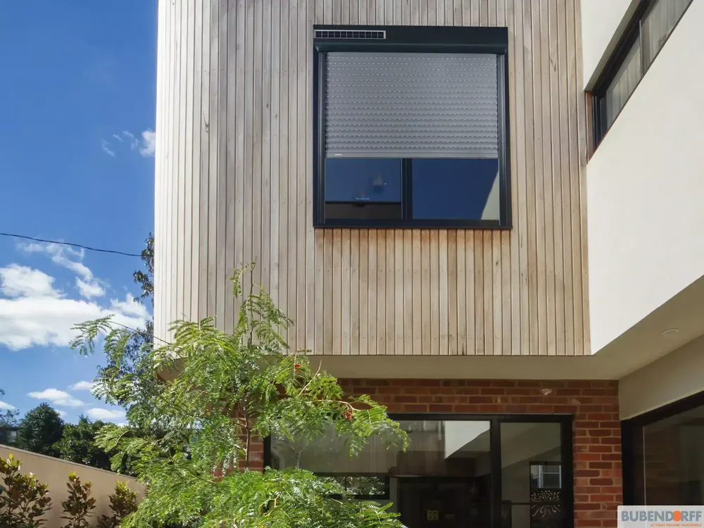 Volet roulant solaire gris BUBENDORFF sur mesure, installé sur façade moderne avec bardage bois.
