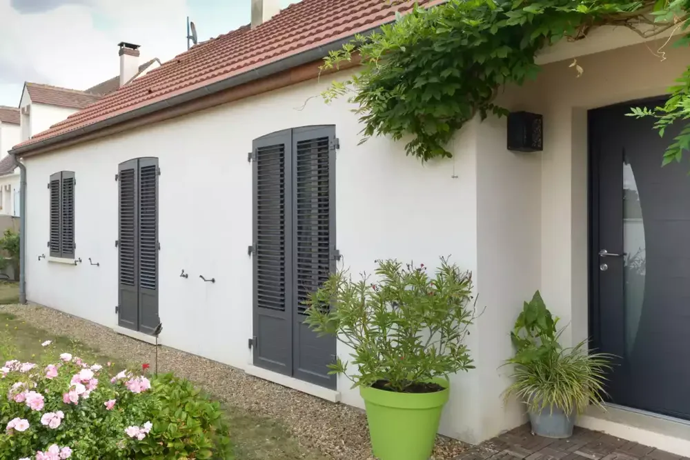 Façade de maison rénovée avec des volets battants gris foncé en PVC sur des portes-fenêtres à Pau.
