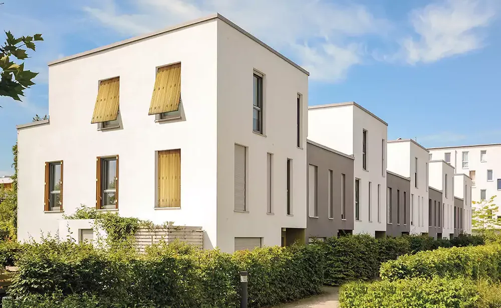 Volets persiennes en bois installés sur la façade blanche d'une résidence récente dans le Bearn.